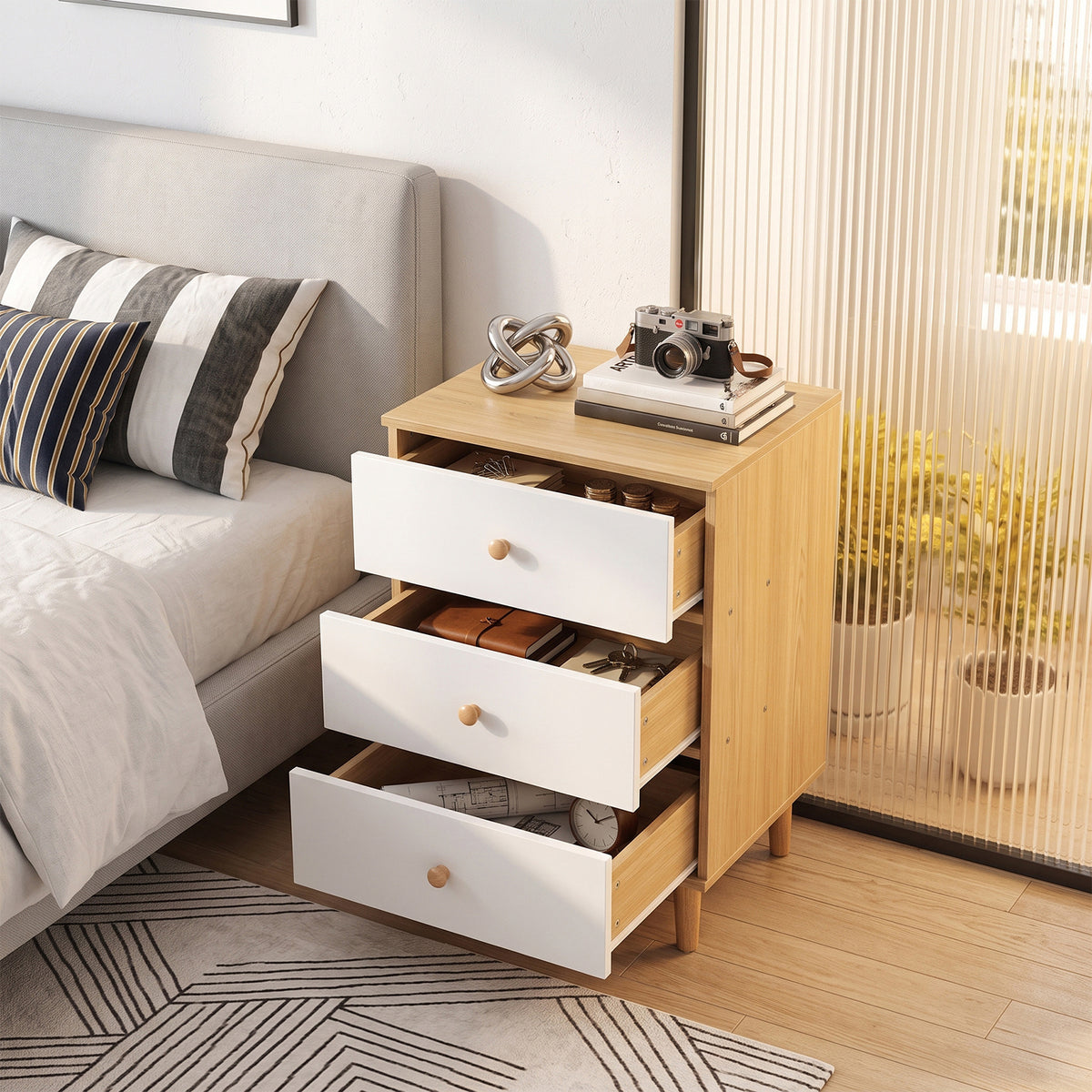 Three-drawer nightstand with drawers pulled out in a bedroom