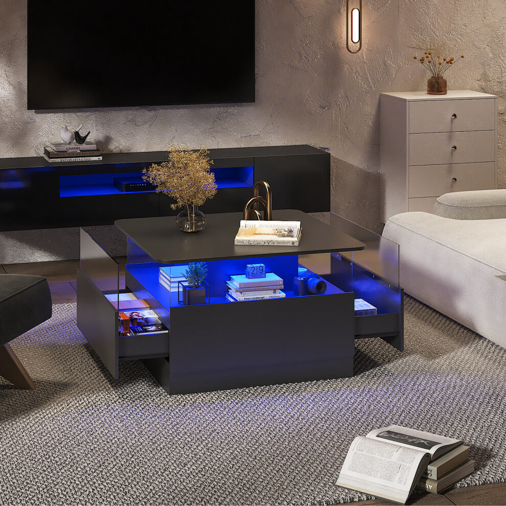 Black square LED coffee table with storage glowing blue in a TV room, side drawers open and books on the display shelf