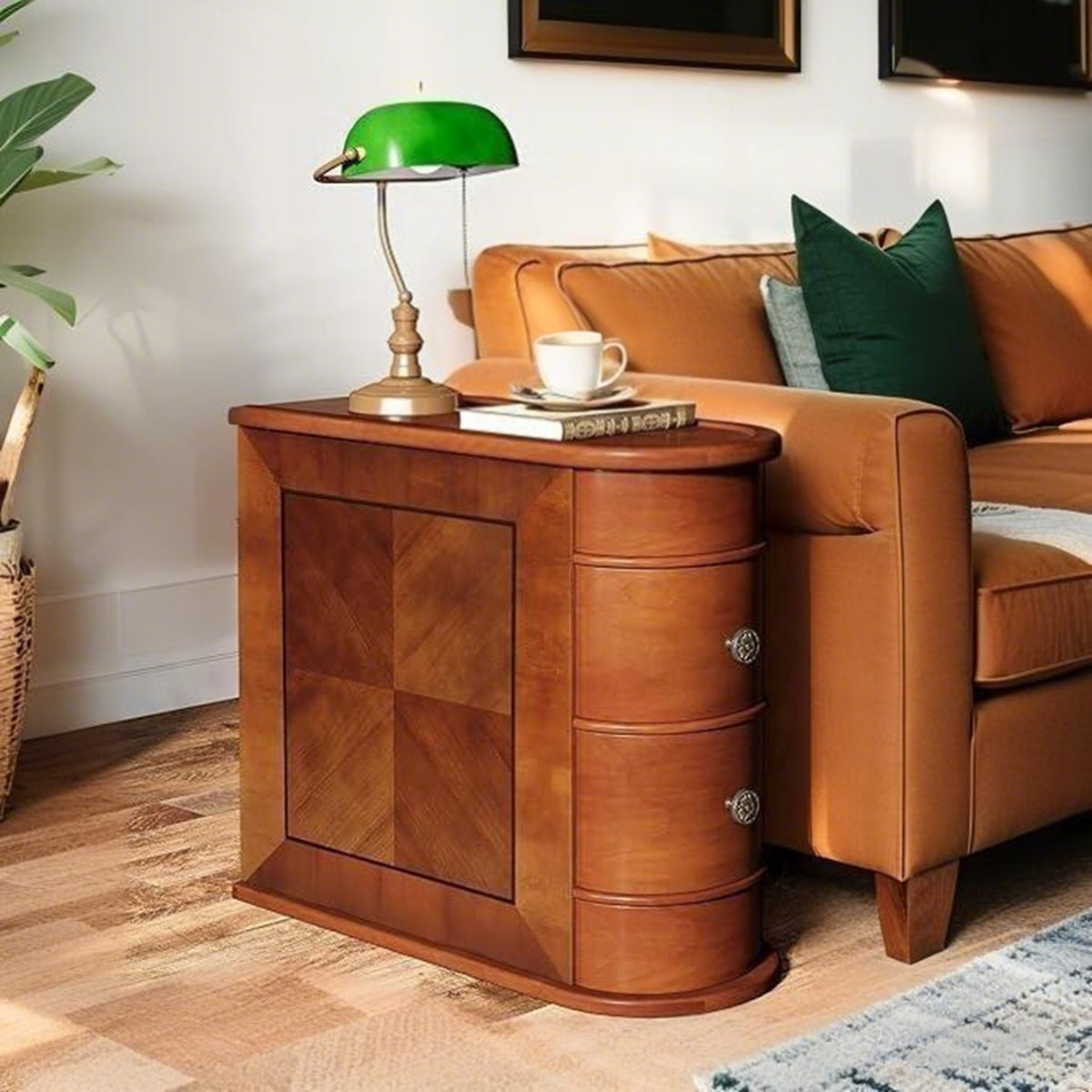 Brown drawer side table with a green banker lamp beside a tan leather sofa
