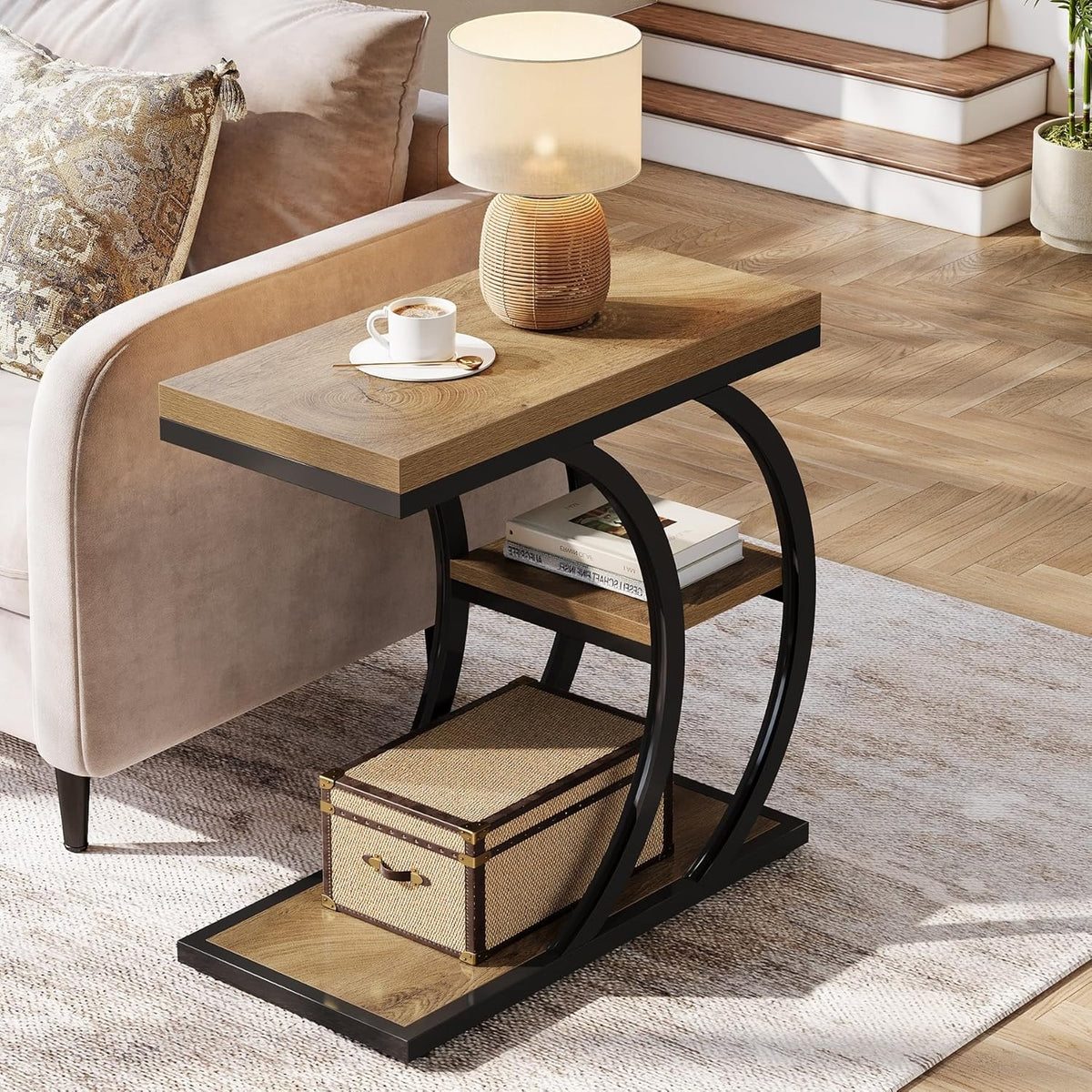 C shaped side table in natural wood effect and black metal beside a sofa with a lamp and tea cup