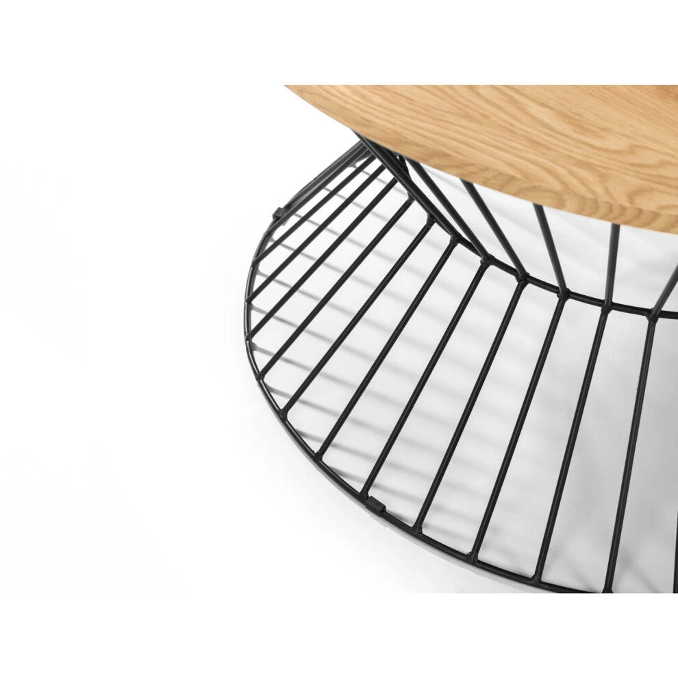 Close-up of black wire hourglass frame under light oak-effect round table top