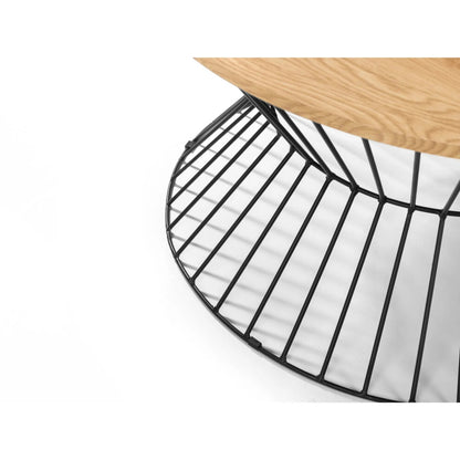 Close-up of black wire hourglass frame under light oak-effect round table top