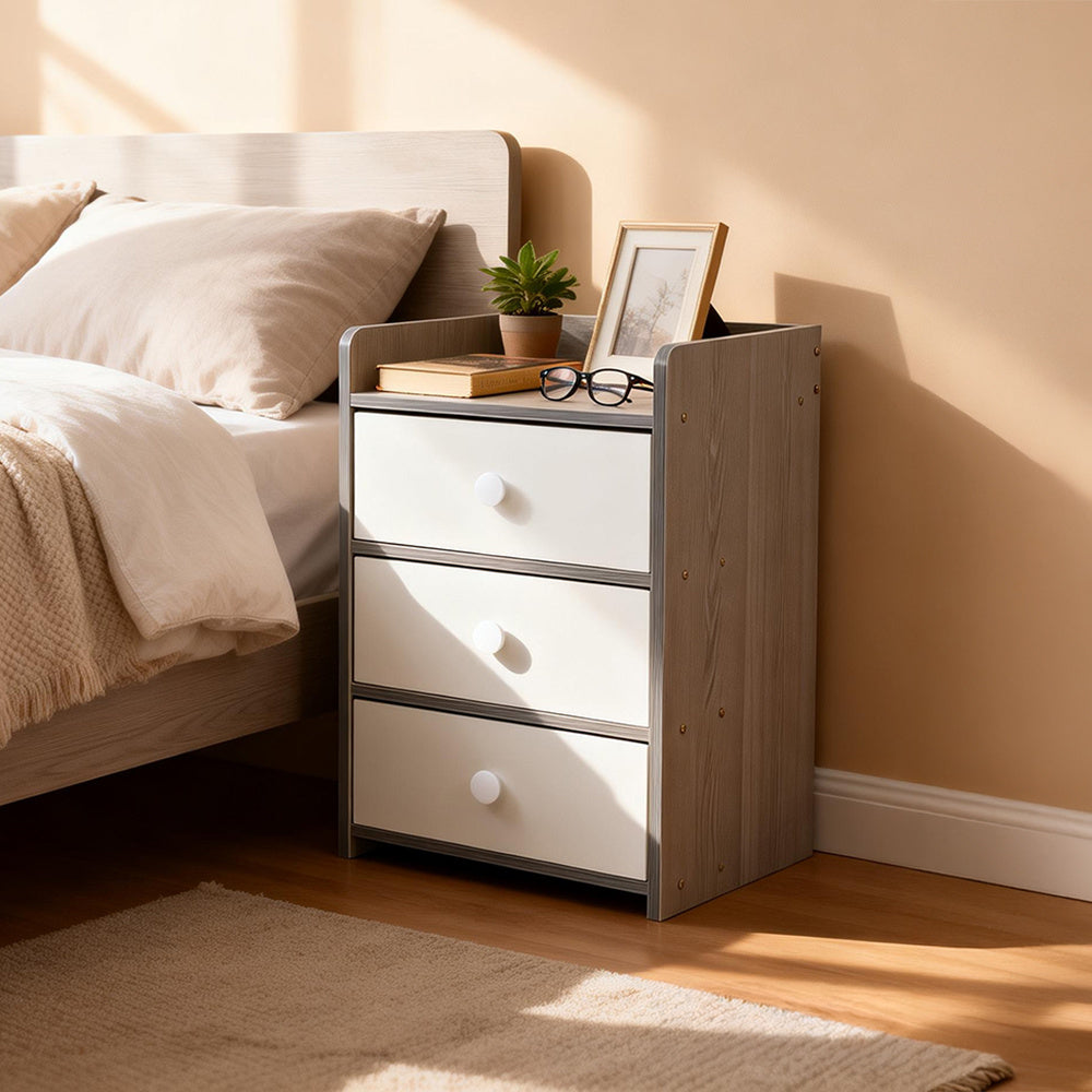 Grey nightstand with three white drawers holding a photo frame and glasses