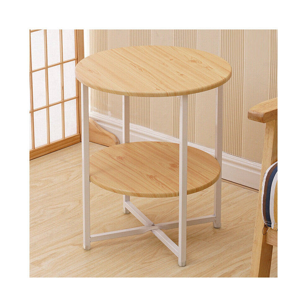 Light wood round side table with lower shelf and white legs next to a wooden armchair