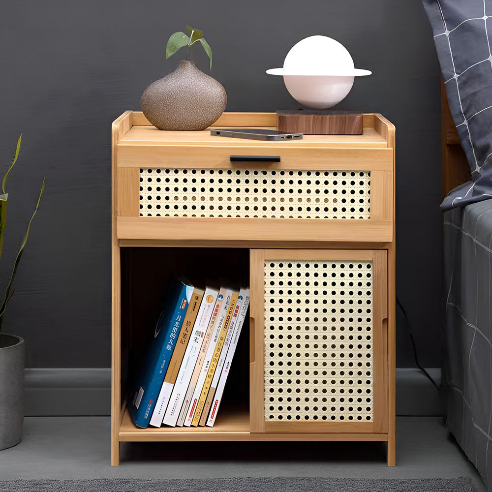 Natural wood side table with open cubby holding books next to a bed with a lamp and vase on top