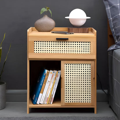Natural wood side table with open cubby holding books next to a bed with a lamp and vase on top