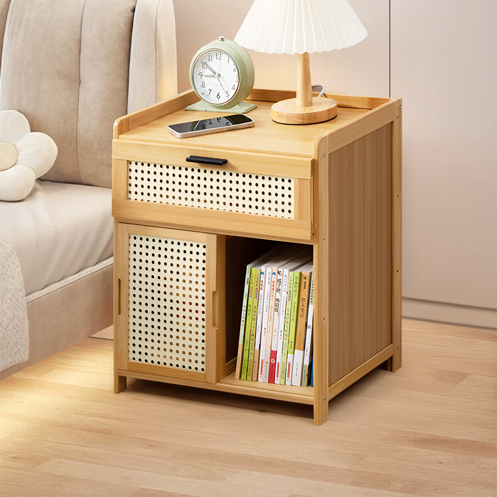 Rattan side table in natural bamboo with a woven drawer, sliding door and books beside a bed