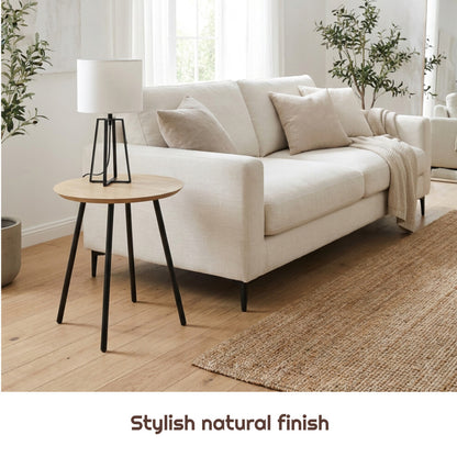 Scandi round side table with black metal legs holding a table lamp beside a cream sofa on oak flooring