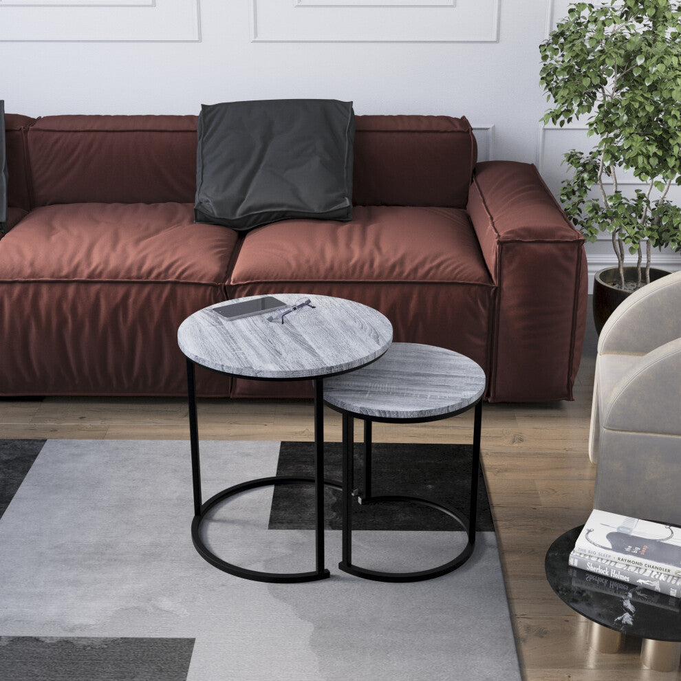 Set of 2 grey round side tables with black C-shaped bases in front of a red sofa on a grey rug