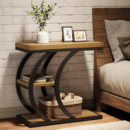 Slim bedside C shaped side table with shelves next to a bed with a plant and photo frames