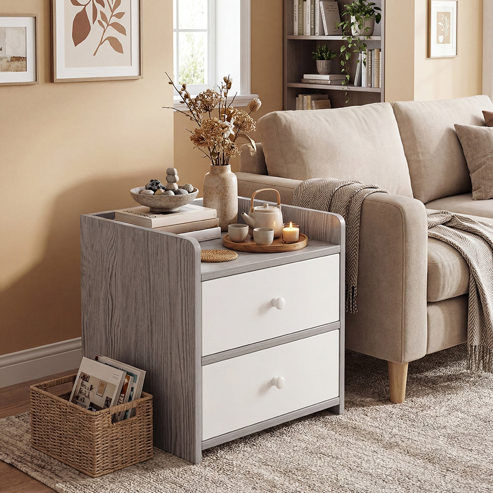 Small grey side table with drawers holding a teapot, candles and a bowl on top