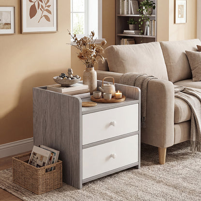 Small grey side table with drawers holding a teapot, candles and a bowl on top
