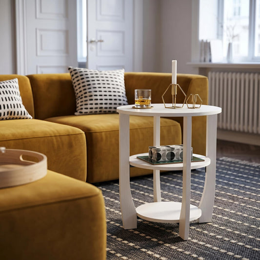 Small white coffee table with three round tiers beside a mustard velvet sofa