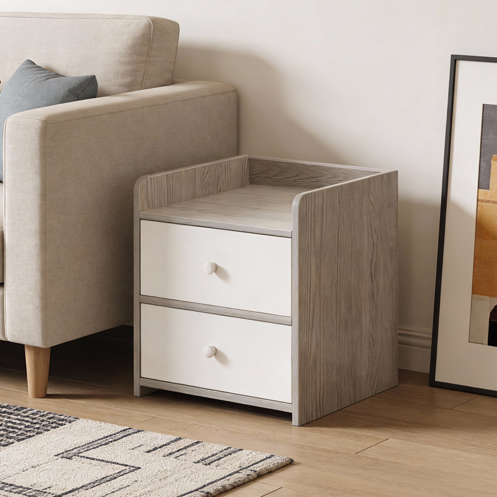 Two-drawer cabinet side table next to a beige armchair in a living room