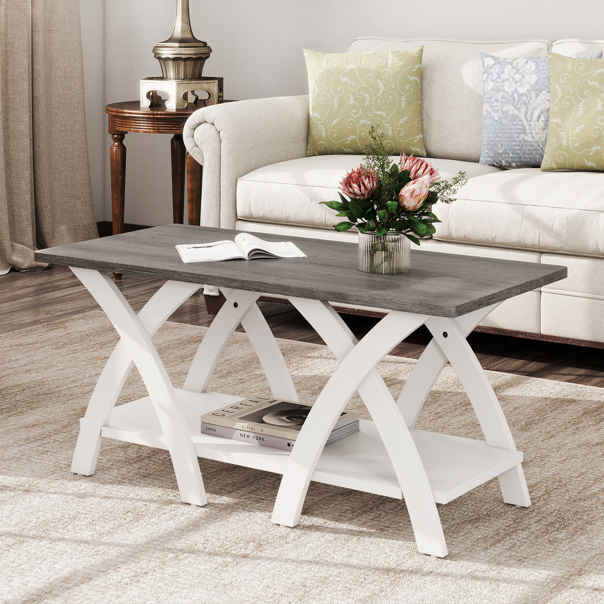 Two-tier grey woodgrain coffee table with white curved X-legs in front of a cream sofa