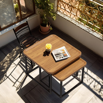 Top view of walnut tray-top square tables nested on a sunny balcony with a bistro chair