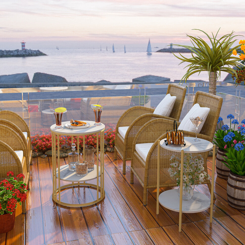 White and gold round side tables between rattan chairs on a seaside terrace