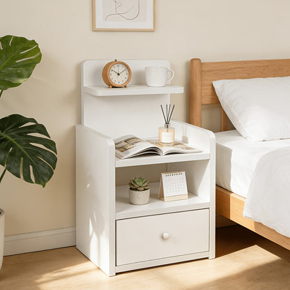 White bedside table with plant, clock and open shelf beside a wooden bed