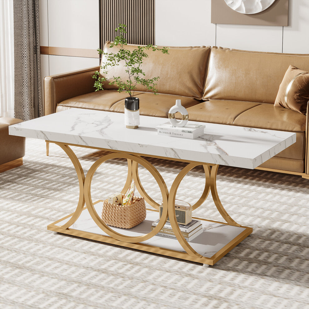 White faux marble rectangular coffee table with interlocking gold rings and open shelf by a tan leather sofa