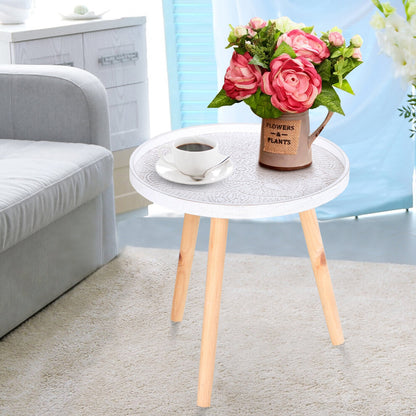 White mandala round side table with whitewashed carved top and wooden legs holding coffee and flowers beside a grey sofa