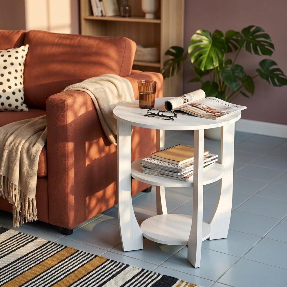 White round side table with storage shelves holding magazines next to a terracotta sofa