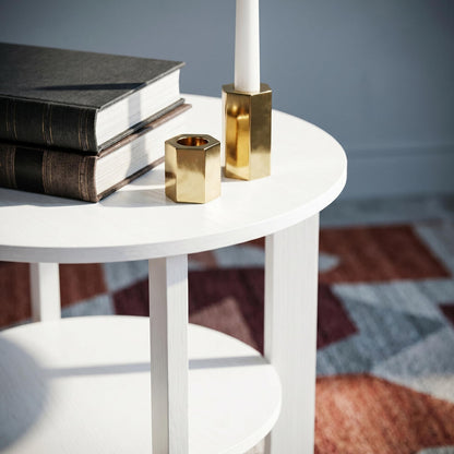 Close-up of white woodgrain effect round table top with books and brass candle holders